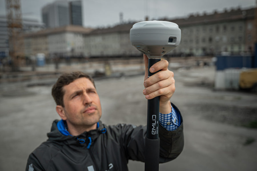 A surveyor using an Emlid Reach RS4 Pro GNSS receiver on a construction site