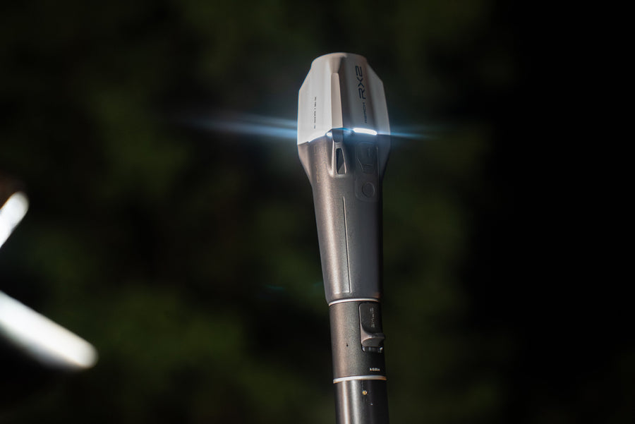 An Emlid Reach RX2 GNSS rover on a pole, working in low light
